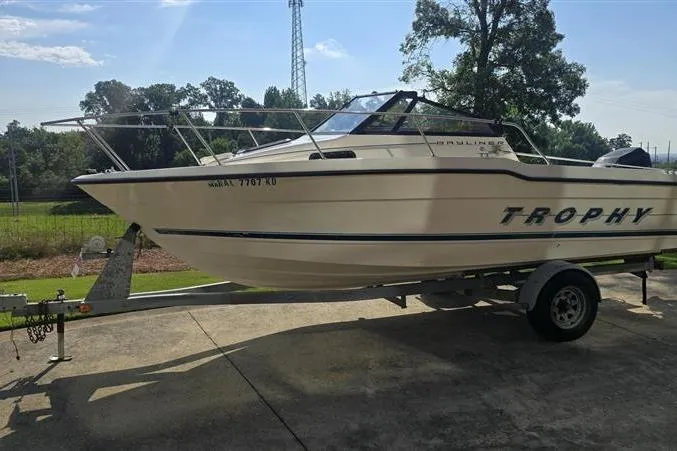 The Image of 1996 Bayliner Trophy Walkaround boat on trailer, parked outdoors. - 1
