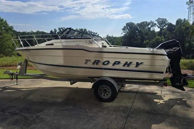Slide: The Image of 1996 Bayliner Trophy Walkaround boat on trailer, parked outdoors under a clear sky. - 2