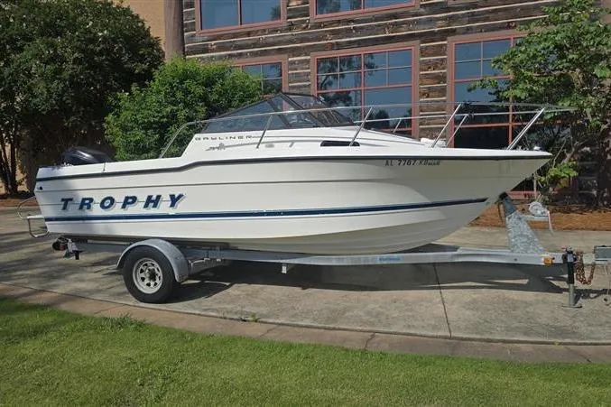 Slide: The Image of 1996 Bayliner Trophy Walkaround boat on trailer, parked outdoors near a building. - 4