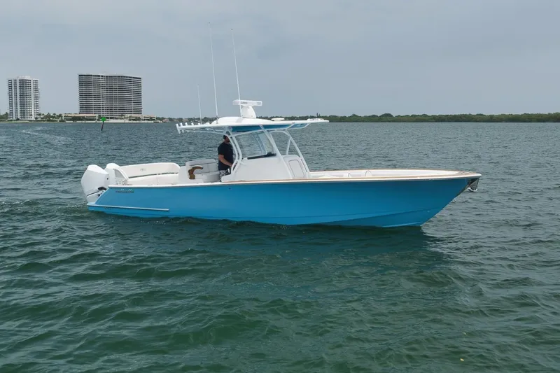 The Image of 2023 Valhalla Boatworks V-33 in blue, cruising on open water near city skyline. - 1