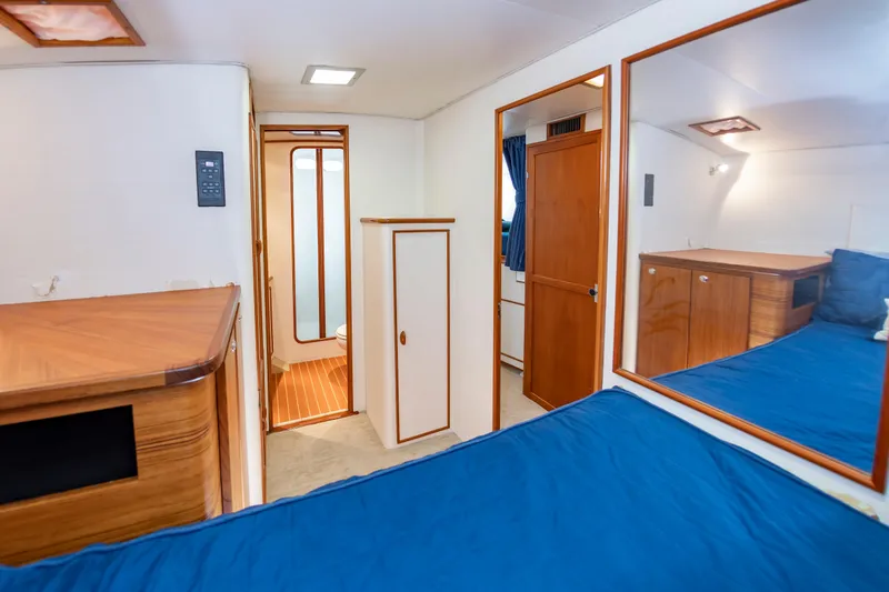 Slide: The Image of Interior of 1993 Custom Carolina Scarborough 56 Convertible yacht, featuring wood accents and blue bedding. - 27