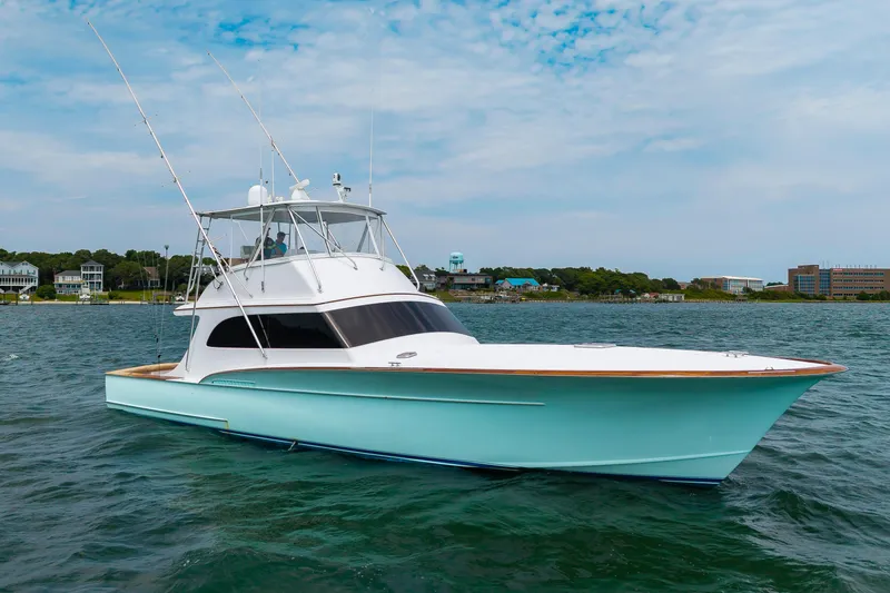 Slide: The Image of 1993 Custom Carolina Scarborough 56 Convertible yacht on calm water, with coastal buildings in the background. - 55