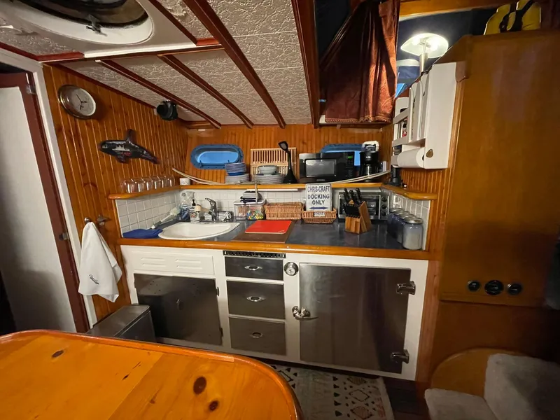 Slide: The Image of 1951 Chris-Craft Catalina kitchen with wooden cabinetry, stainless steel appliances, and nautical decor. - 4