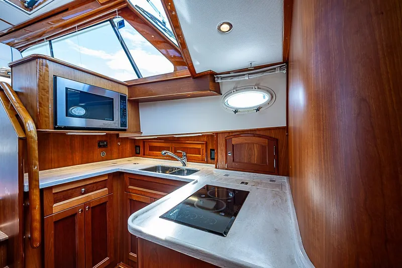 Slide: The Image of Luxurious 2015 Hinckley Talaria 48 yacht kitchen with wood cabinetry and modern appliances. - 17