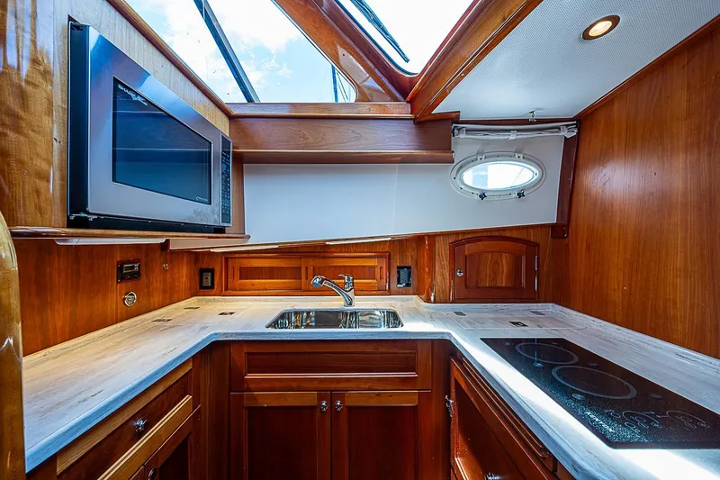 Slide: The Image of Luxurious 2015 Hinckley Talaria 48 yacht kitchen with wood cabinetry and modern appliances. - 18