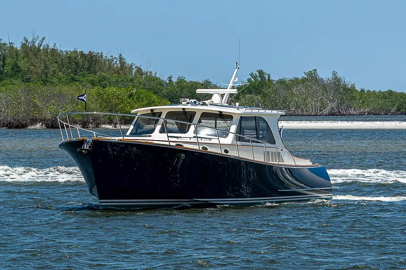 Slide: The Image of 2015 Hinckley Talaria 48 yacht cruising on a sunny day near lush shoreline. - 2