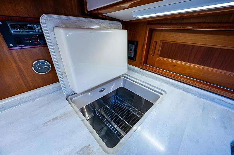 Slide: The Image of Interior of 2015 Hinckley Talaria 48 yacht, featuring a built-in freezer and wooden cabinetry. - 20