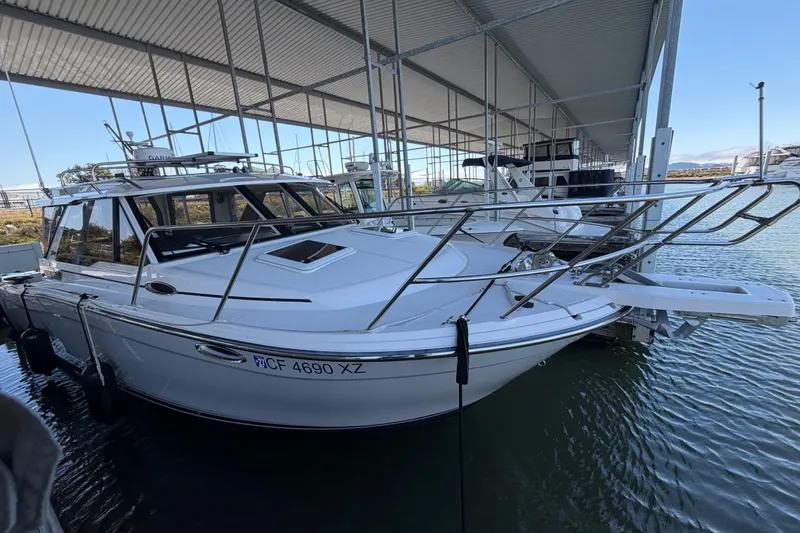 Slide: The Image of 2023 Cutwater C-288 Coupe boat docked under a covered marina. - 2