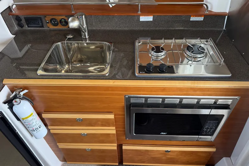 Slide: The Image of 2023 Cutwater C-288 Coupe kitchen with sink, stove, microwave, and fire extinguisher. - 29