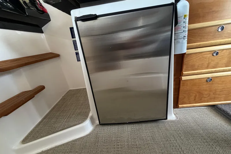 Slide: The Image of Interior of 2023 Cutwater C-288 Coupe featuring a compact stainless steel refrigerator. - 31