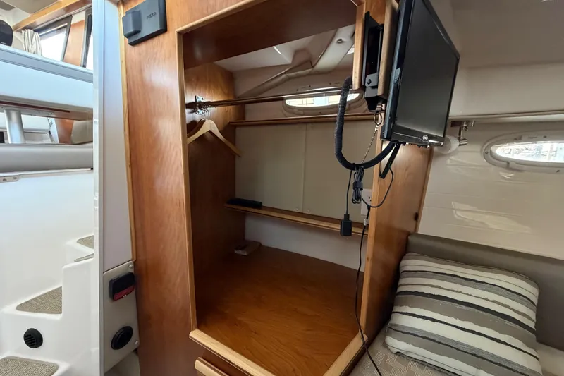 Slide: The Image of 2023 Cutwater C-288 Coupe interior with wooden closet, TV, and striped cushion. - 48