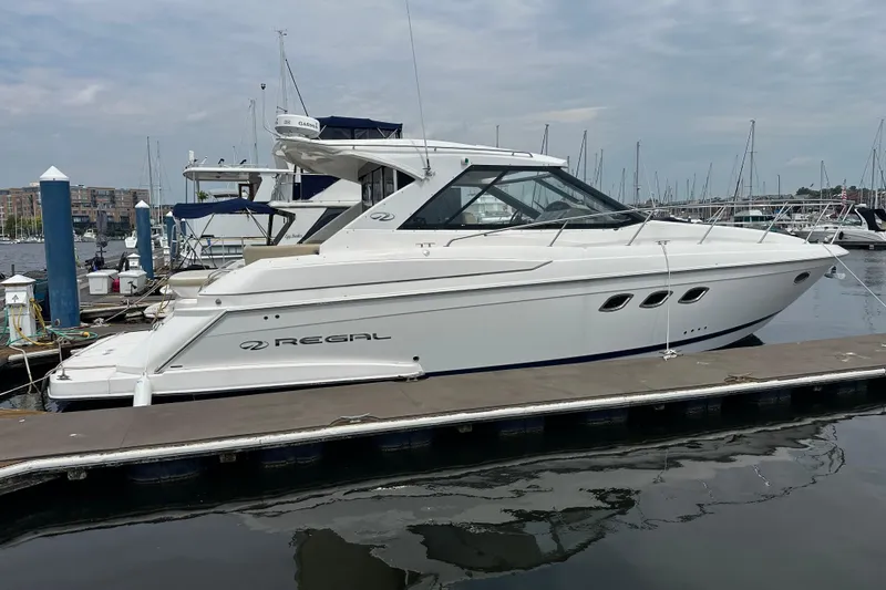 Slide: The Image of 2012 Regal 42 Sport Coupe yacht docked at marina under cloudy sky. - 1