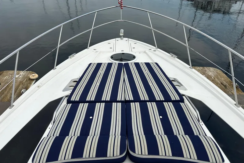 Slide: The Image of 2012 Regal 42 Sport Coupe bow with striped cushions on calm water. - 9