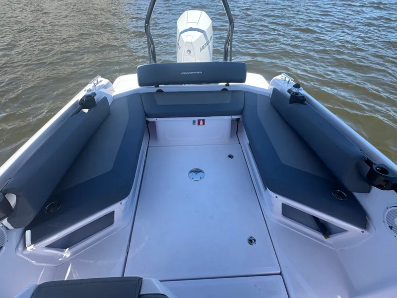 Slide: The Image of The boat features an open seating area with gray cushions, floating on the water. - 2