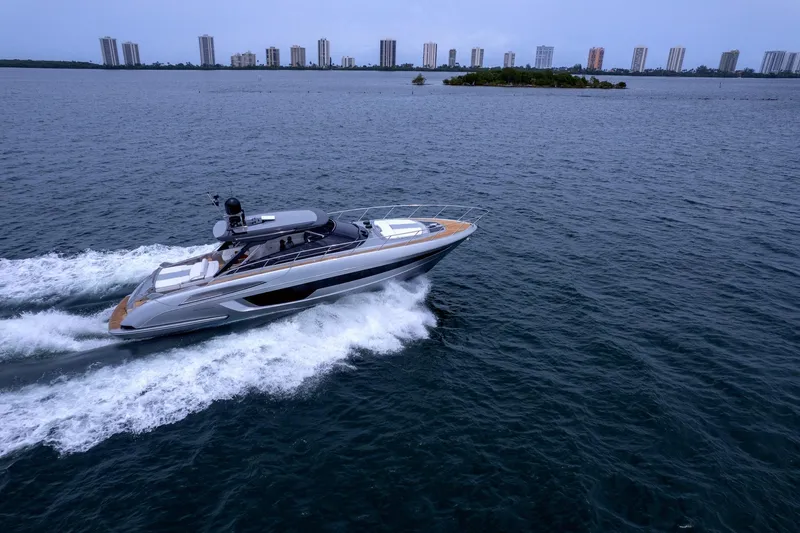 Slide: The Image of 2022 Riva 56' Rivale yacht cruising on open water with city skyline backdrop. - 6