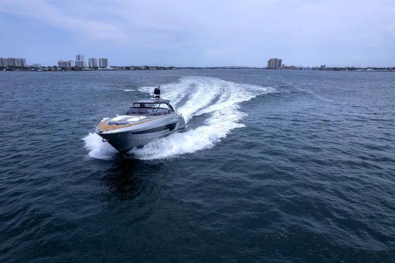 Slide: The Image of 2022 Riva 56' Rivale yacht cruising on open water with city skyline backdrop. - 8