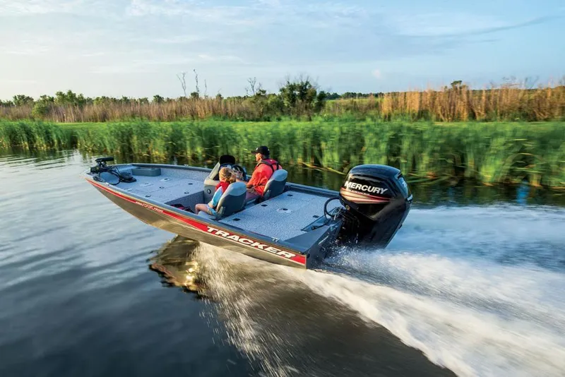 Slide: The Image of A Tracker boat speeds on calm water, surrounded by reeds and trees. - 14