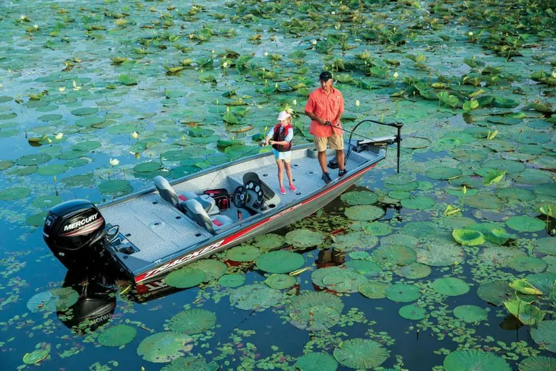 Slide: The Image of A boat with two people is on water covered with lily pads. - 18