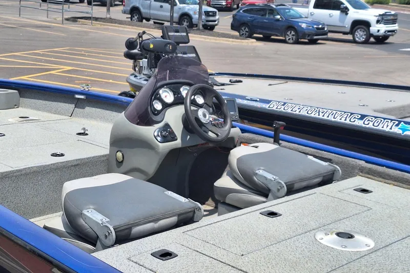 Slide: The Image of 2016 Tracker Pro Team 175 TF boat interior with steering wheel and seating in a parking lot. - 4
