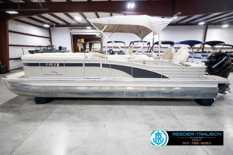 Slide: The Image of 2013 Bennington 2550 RBR pontoon boat in indoor showroom with canopy and Mercury engine. - 12