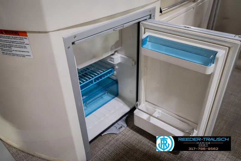 Slide: The Image of Open mini fridge on 2013 Bennington 2550 RBR boat, showcasing interior storage space. - 37