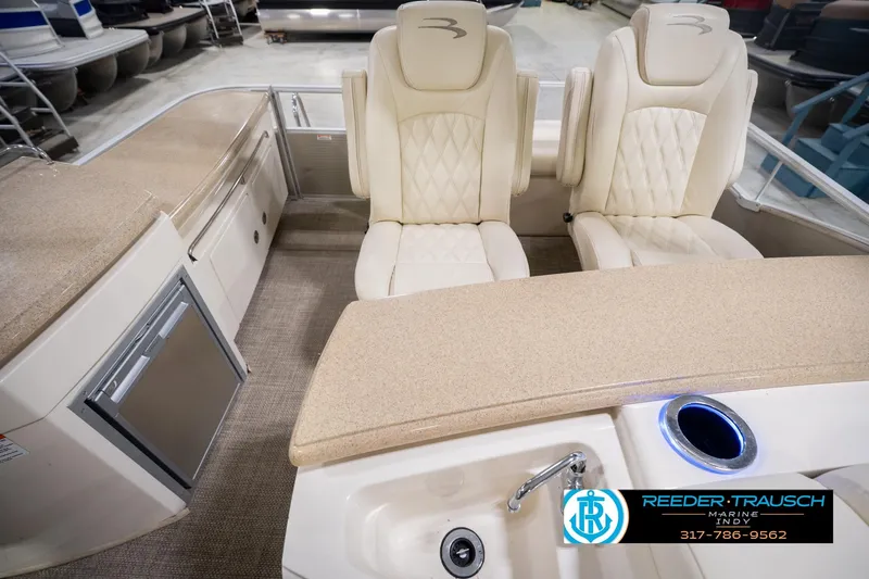 Slide: The Image of 2013 Bennington 2550 RBR boat interior with beige seating and modern amenities. - 21