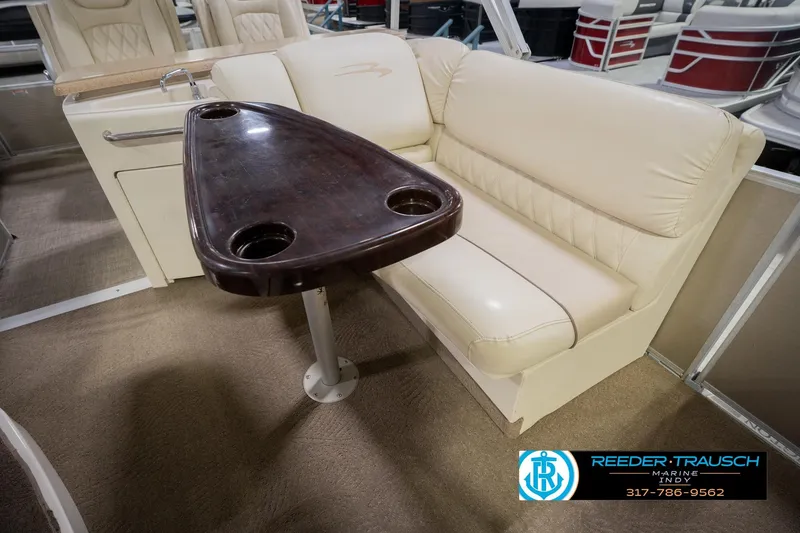 Slide: The Image of 2013 Bennington 2550 RBR boat interior with beige seating and wooden table. - 30
