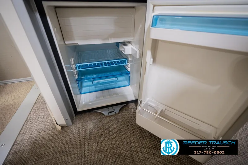 Slide: The Image of Open refrigerator inside a 2013 Bennington 2550 RBR boat, showcasing storage compartments. - 58