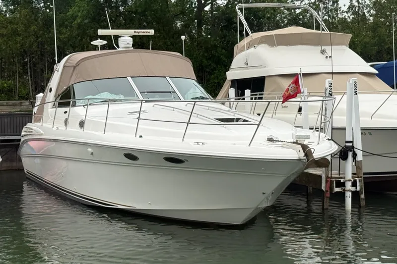 The Image of 1998 Sea Ray Sundancer 400 yacht docked at marina, featuring sleek design and beige canopy. - 0