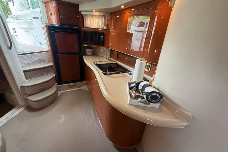 Slide: The Image of 1998 Sea Ray Sundancer 400 yacht interior with kitchenette, featuring wood cabinetry and modern appliances. - 25