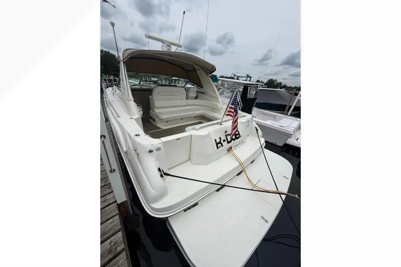 Slide: The Image of 1998 Sea Ray Sundancer 400 yacht docked, featuring spacious seating and American flag. - 8