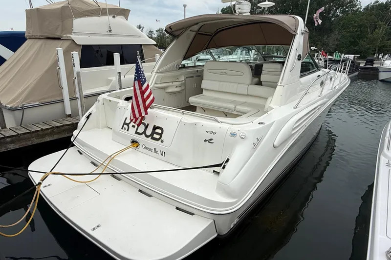 Slide: The Image of 1998 Sea Ray Sundancer 400 docked, featuring spacious deck and American flag. - 9