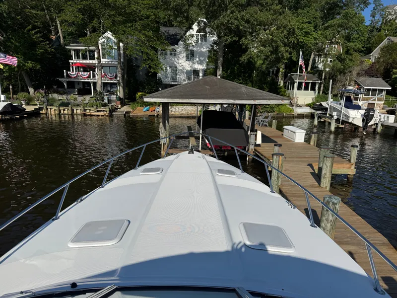 Slide: The Image of Boat at a dock with houses in the background, surrounded by trees. - 22