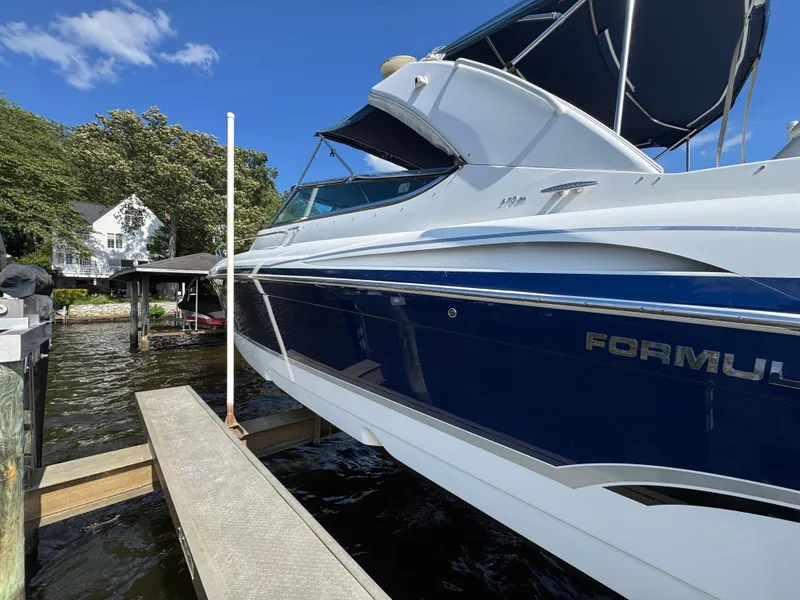 Slide: The Image of A blue and white boat docked, surrounded by trees and a house. - 5