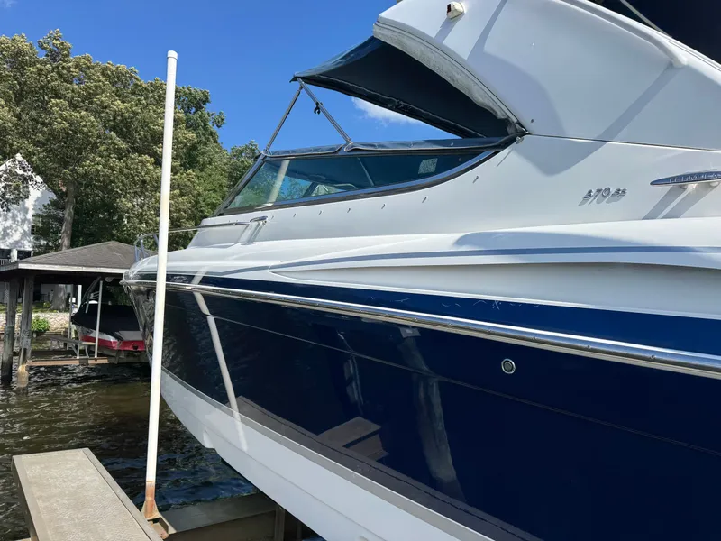 Slide: The Image of A blue and white boat docked, surrounded by trees and clear sky. - 7