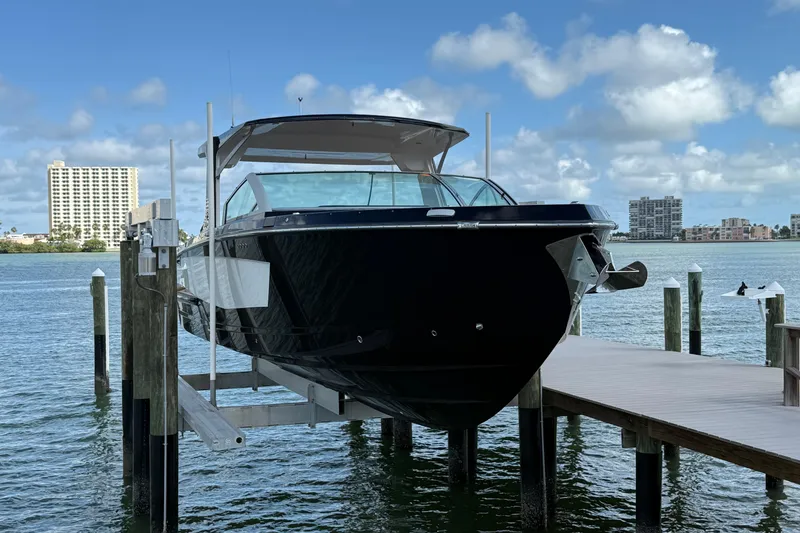 Slide: The Image of 2023 Aviara AV36 OB boat docked on a lift, with waterfront cityscape background. - 3