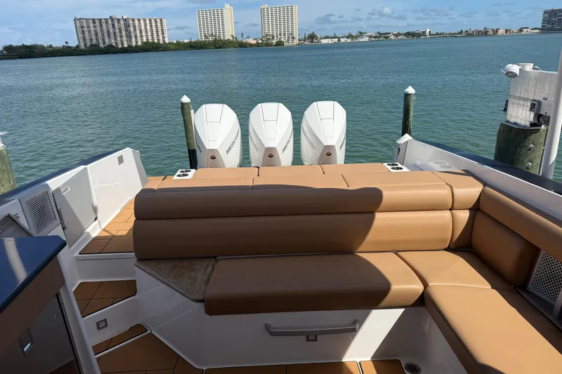 Slide: The Image of 2023 Aviara AV36 OB boat with tan seating and triple outboard motors on a scenic waterfront. - 44