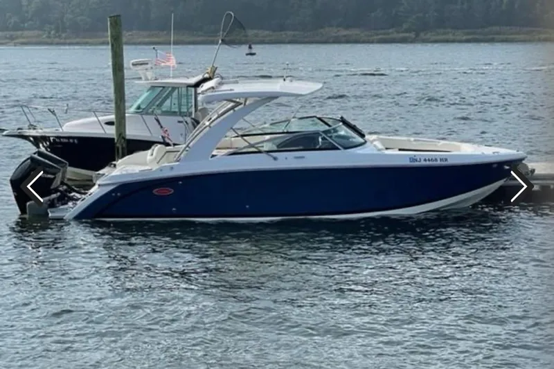 The Image of 2021 Cobalt 30SC boat docked on calm water, featuring sleek blue and white design. - 0