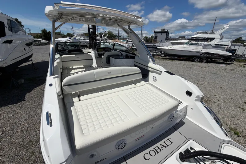 Slide: The Image of 2021 Cobalt 30SC boat with white seating, docked outdoors under a blue sky. - 8