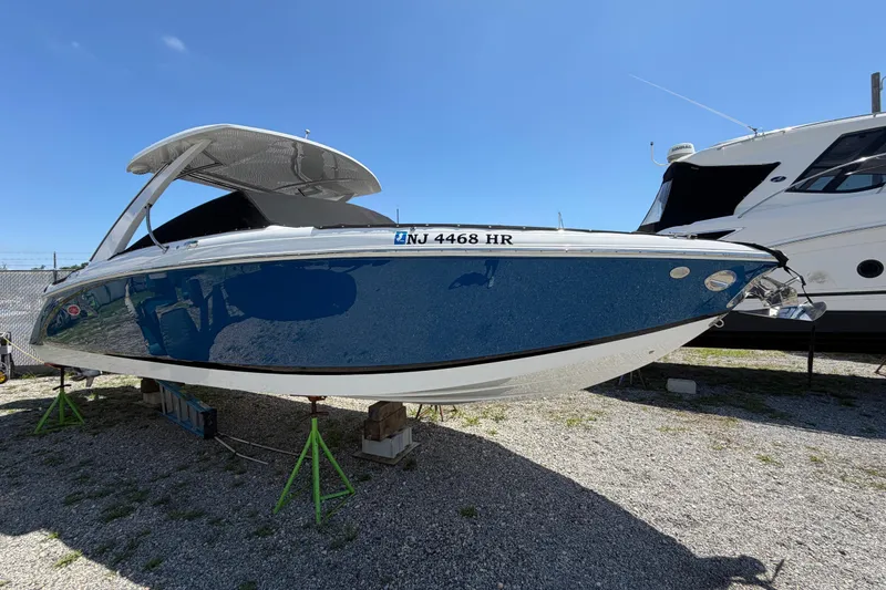 Slide: The Image of 2021 Cobalt 30SC boat on stands, blue hull, sunny day, marina setting. - 3
