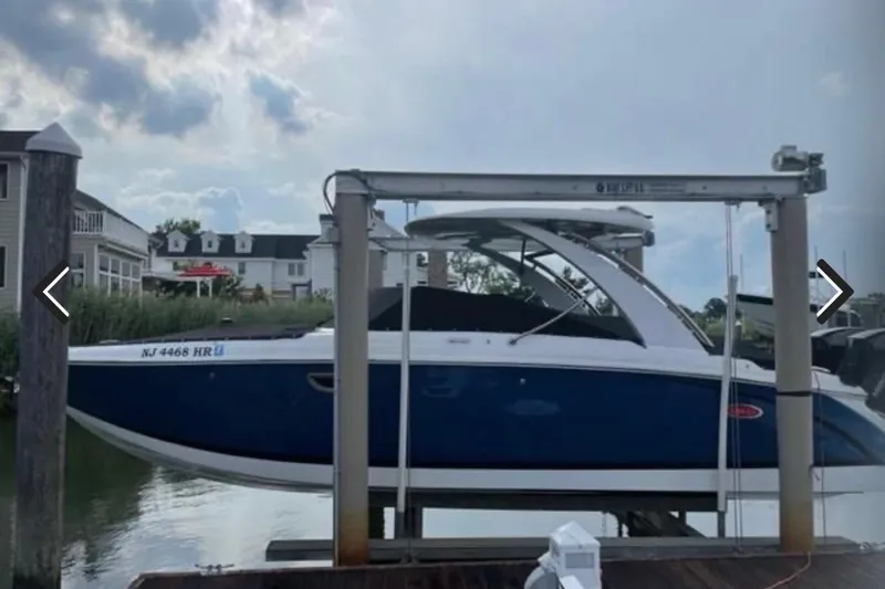 Slide: The Image of 2021 Cobalt 30SC boat docked, blue and white design, overcast sky background. - 2