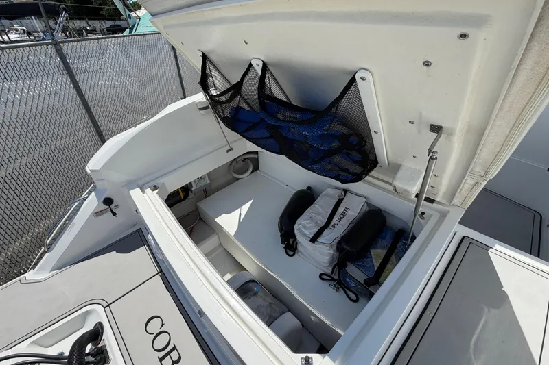 Slide: The Image of Open storage compartment on 2021 Cobalt 30SC boat, featuring life jackets and accessories. - 12