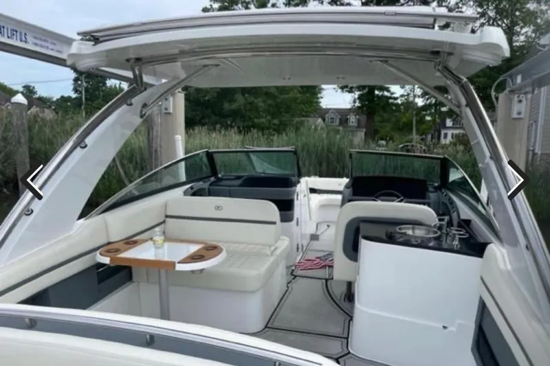 Slide: The Image of 2021 Cobalt 30SC boat interior with seating and table, docked near greenery. - 5