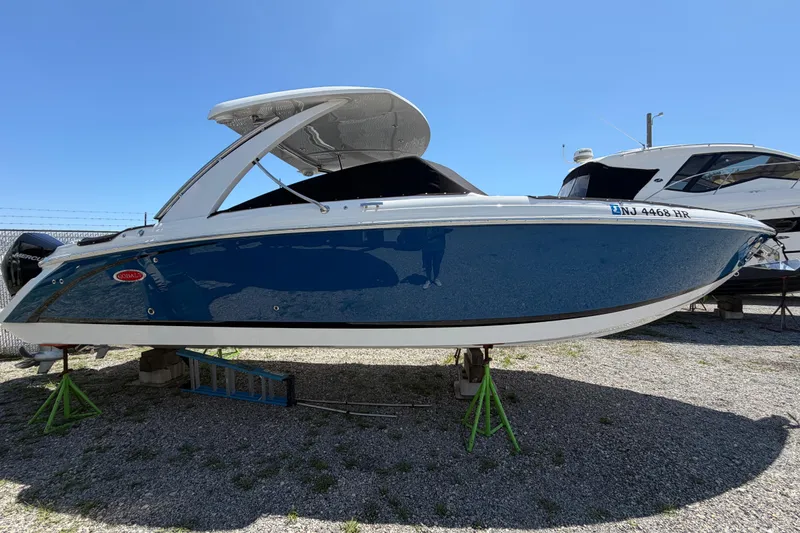 Slide: The Image of 2021 Cobalt 30SC boat on stands, blue hull, outdoor display. - 2