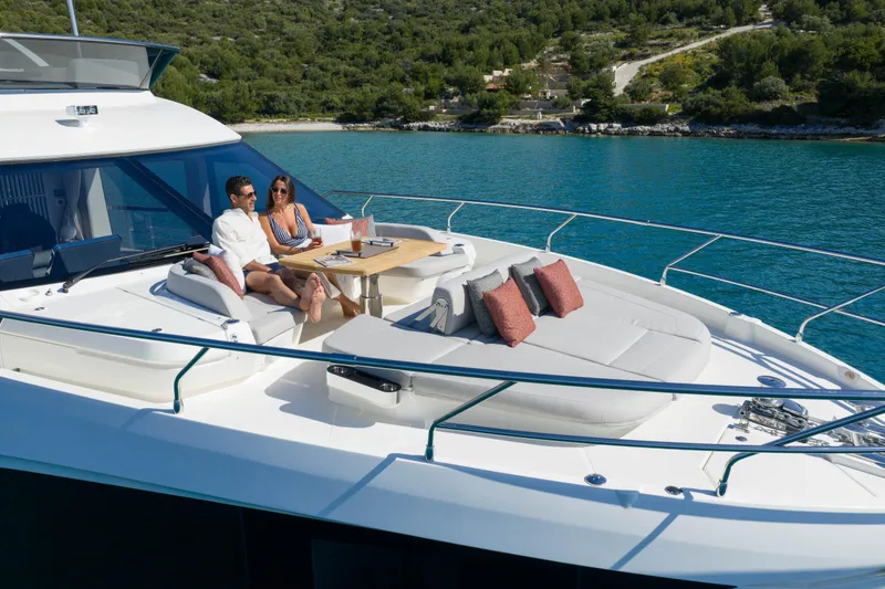 Slide: The Image of Couple relaxing on the deck of a 2027 Absolute 70 Fly yacht, surrounded by scenic waters. - 23
