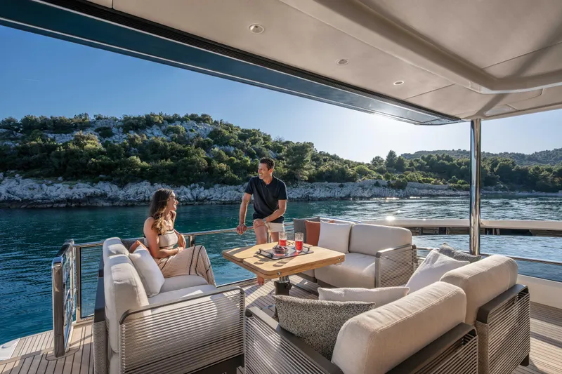 Slide: The Image of Two people relax on a luxurious boat overlooking a wooded coastline. - 12