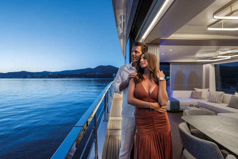 Slide: The Image of A couple stands on a luxurious yacht at sunset, overlooking the water. - 24