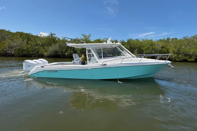 The Image of 2009 Everglades 350LX boat cruising on a sunny day near lush greenery. - 1