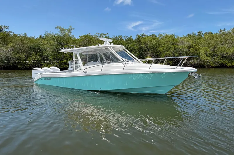 Slide: The Image of 2009 Everglades 350LX boat on calm water, surrounded by lush greenery under a clear blue sky. - 10