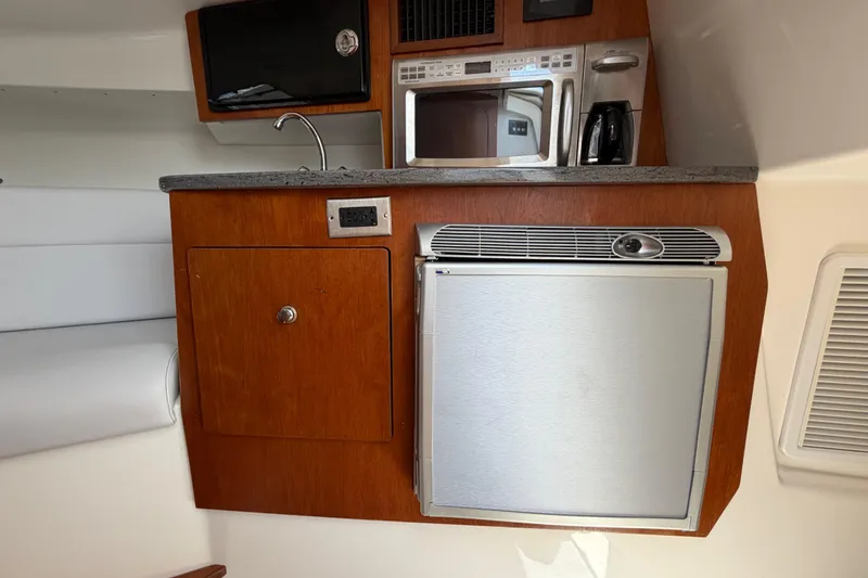 Slide: The Image of Compact kitchen area in a 2009 Everglades 350LX boat with microwave and fridge. - 58